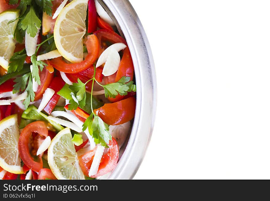 Pot and some raw ingredients on white background. The fish is cooked under the layer of vegetables. Pot and some raw ingredients on white background. The fish is cooked under the layer of vegetables.