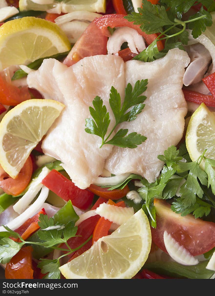 Pot and some raw ingredients on white background. The fish is cooked under the layer of vegetables. Pot and some raw ingredients on white background. The fish is cooked under the layer of vegetables.