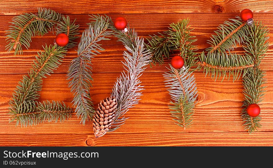 Arrangement of Spruce Branch, Fir Cone and Red Baubles as New Year 2014 closeup on Wooden background