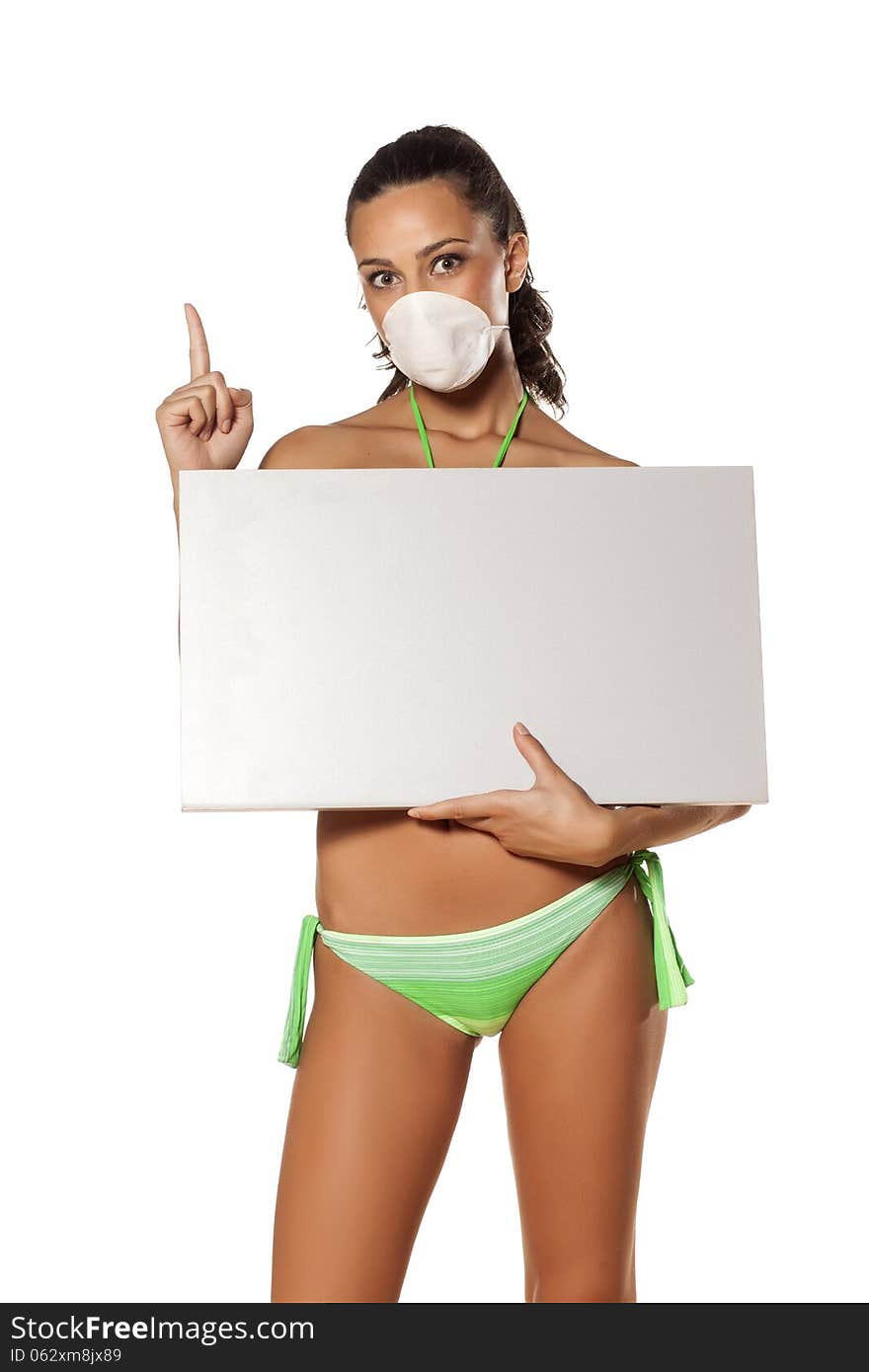 Beautiful brunette with a breathing mask in a bikini holding a blank display and pointing a finger. Beautiful brunette with a breathing mask in a bikini holding a blank display and pointing a finger