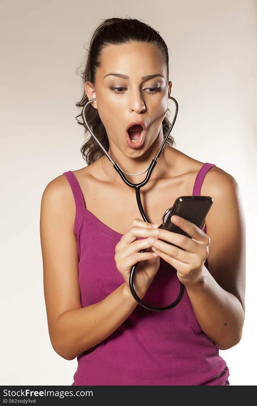 Young beautiful shocked girl uses a stethoscope to tap phones. Young beautiful shocked girl uses a stethoscope to tap phones