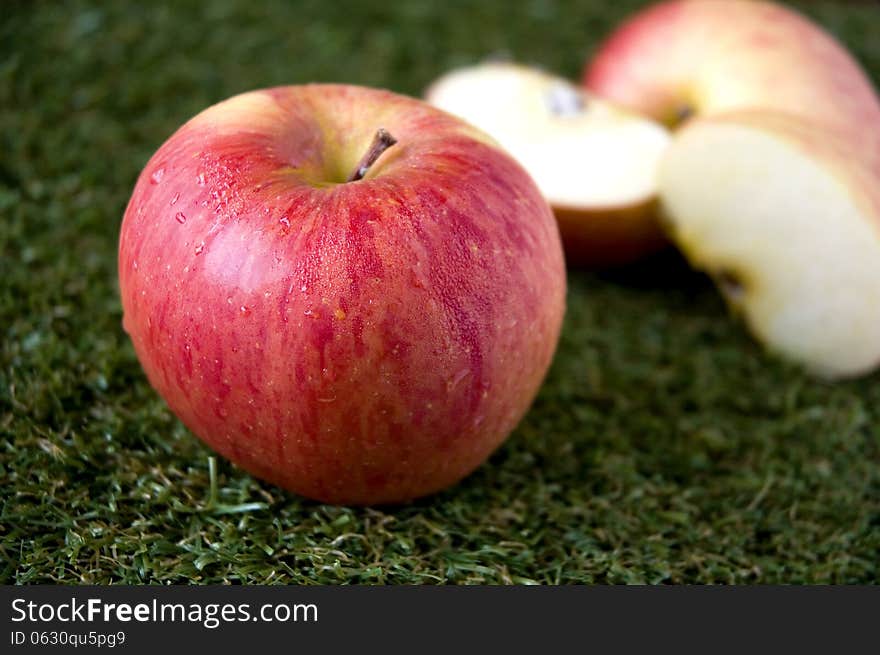 Fresh red apple on green grass with apple slices background