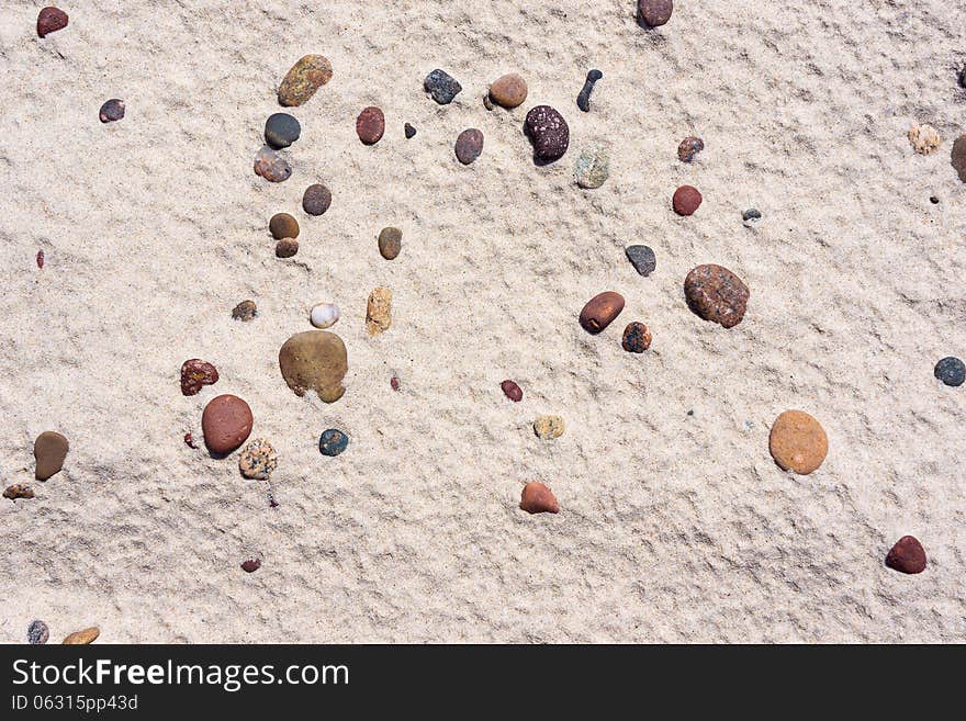 Texture of white sand with  pebbles on Baltic beach.