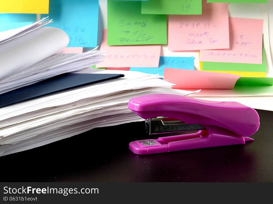 Folders with papers and stapler on a background of multicolored notes. Folders with papers and stapler on a background of multicolored notes