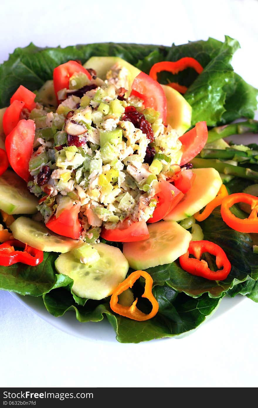 A pretty colorful tempting plate of assorted raw veggies with chicken salad in a flowered tomato. A pretty colorful tempting plate of assorted raw veggies with chicken salad in a flowered tomato.