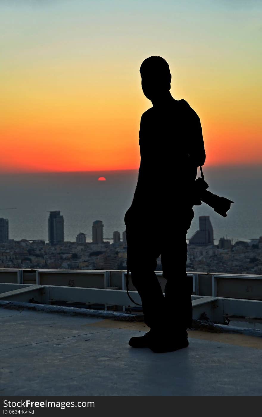 Silhouette of a photographer in the sunset from the roof off skyscraper. Silhouette of a photographer in the sunset from the roof off skyscraper