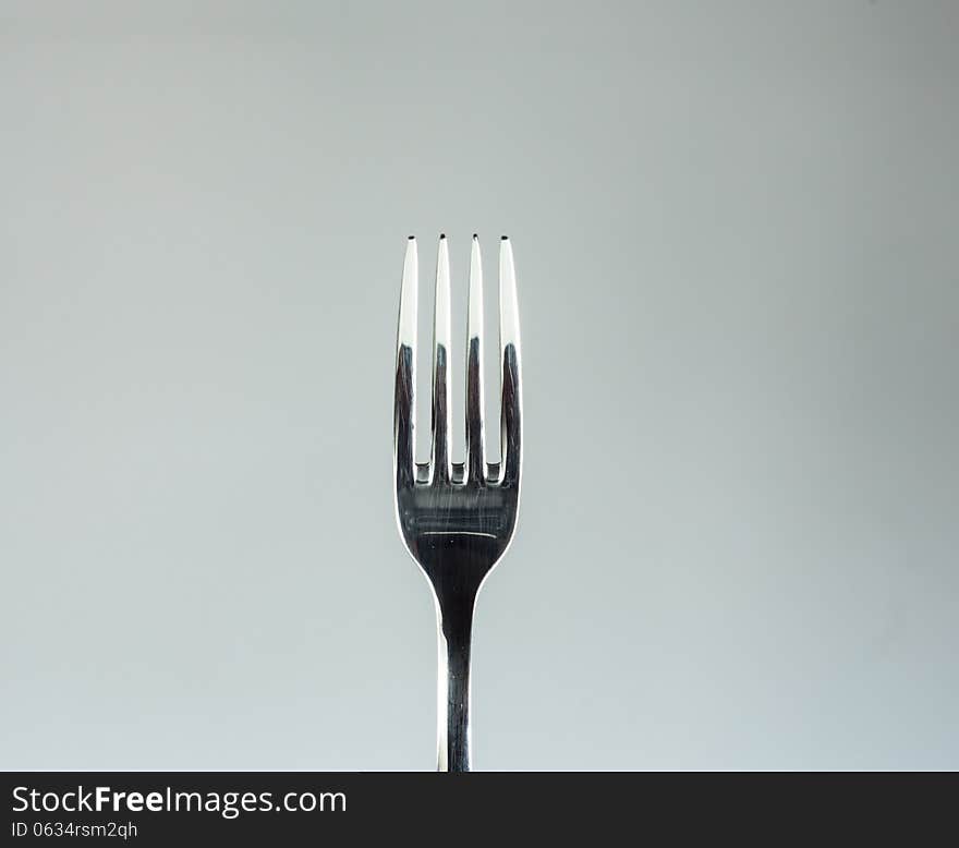 Stainless fork isolated over a light gray background