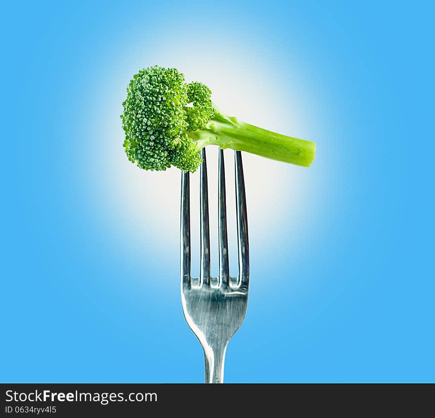 Broccoli on a fork over a blue background. Isolated path on PSD available.