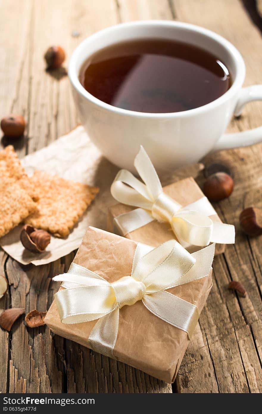 Cup of tea with gift boxes on old wooden background