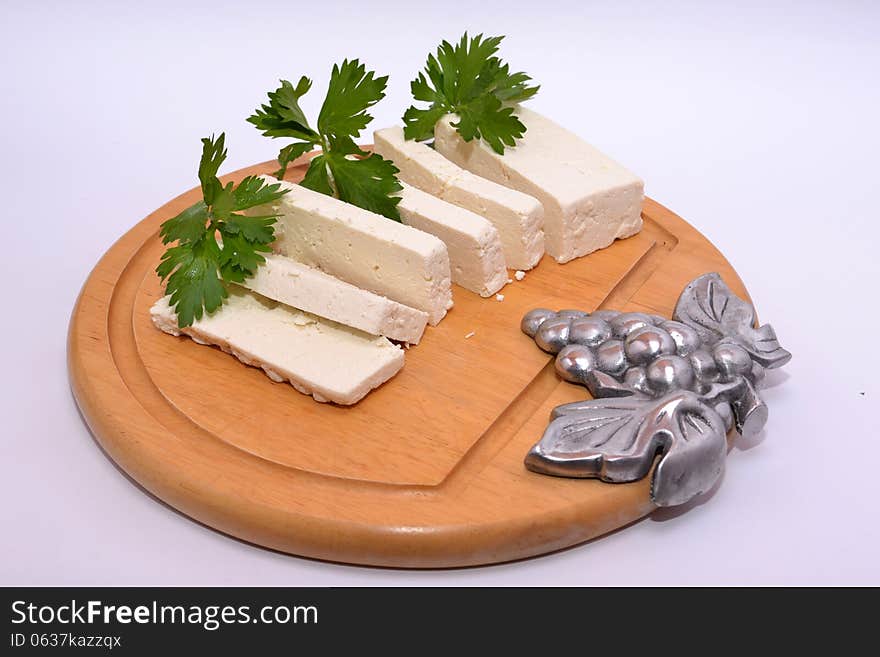 Hard ricotta cheese with celery leaves on kitchen table adorned with a bunch of grapes steel. Hard ricotta cheese with celery leaves on kitchen table adorned with a bunch of grapes steel