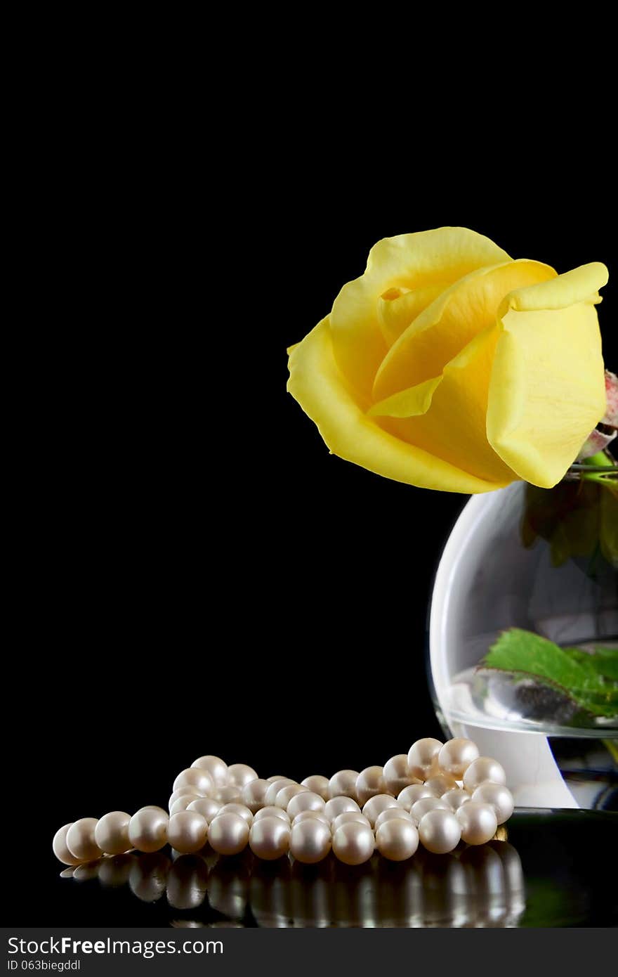 Pearls and yellow rose in a vase on a black background. Pearls and yellow rose in a vase on a black background