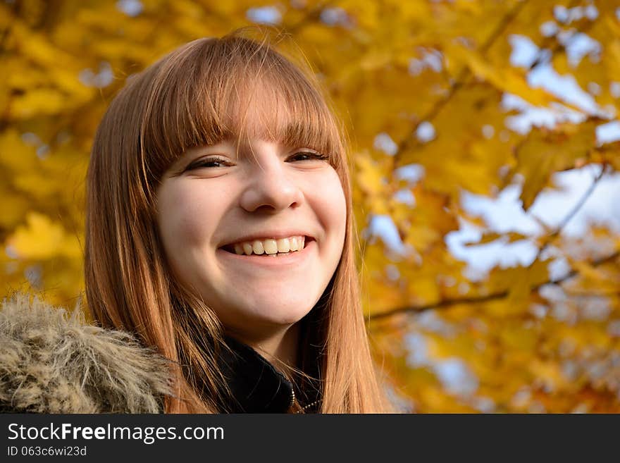 Beautiful young girl with red hair, against the backdrop of golden autumn