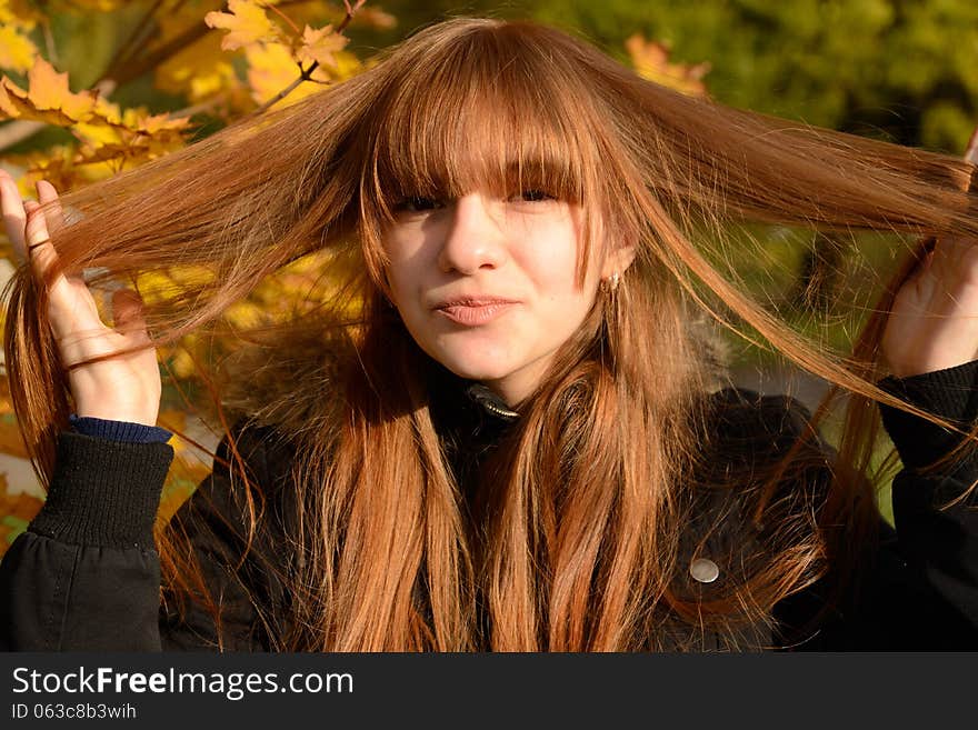 Young red-haired girl holding a strand of hair