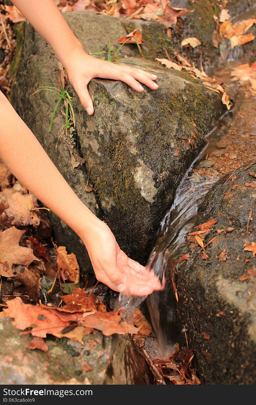 A kid's hand touching a mountain water stream. A kid's hand touching a mountain water stream