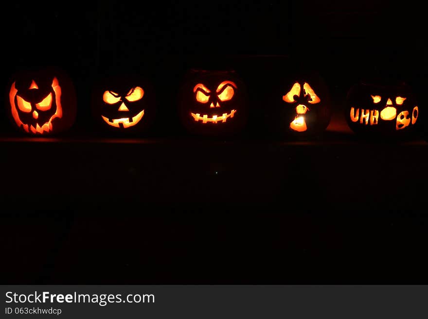 5 Halloween Jack O Lantern pumpkins illuminated in the dark night