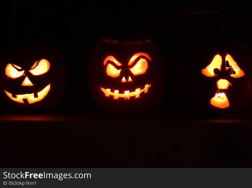 3 Halloween Jack O Lantern pumpkins illuminated in the dark night