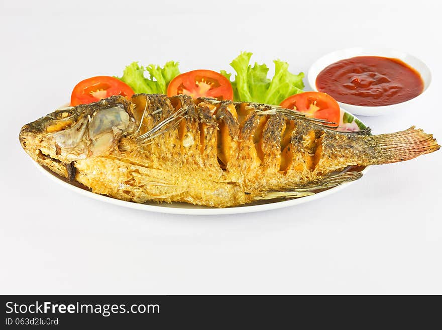 Crispy fried fish with palm oil on white dish. Crispy fried fish with palm oil on white dish.