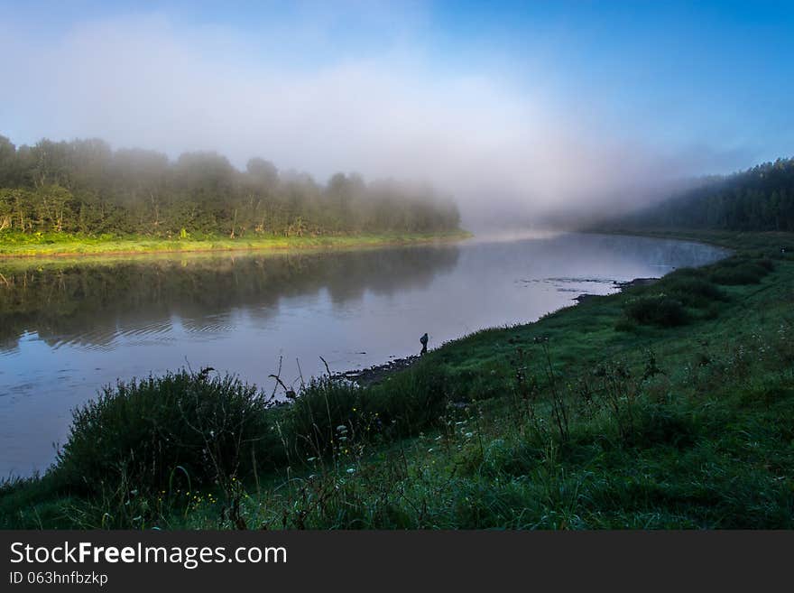 Foggy morning on the river Volga. A light mist rising over the river on a background of blue sky.