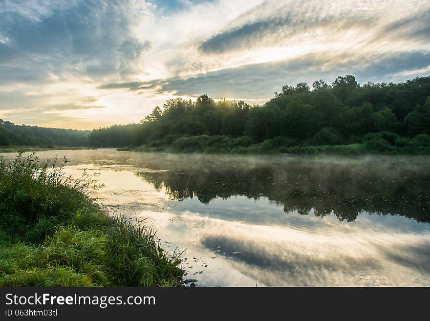 Dawn on the river Volga. Beautiful clouds and mist over the river, a reflection of the clouds and forests in water. Dawn on the river Volga. Beautiful clouds and mist over the river, a reflection of the clouds and forests in water.