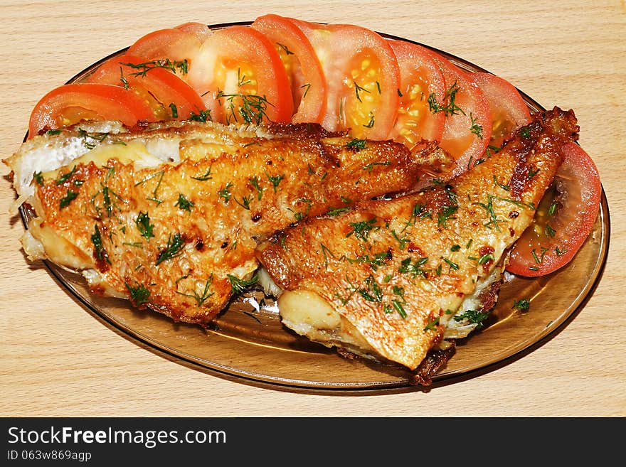 Roasted sea fish with tomato and dill on a glass platter. Roasted sea fish with tomato and dill on a glass platter