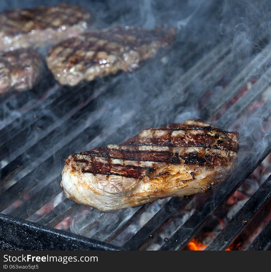 Beef steak cooking on an open flame grill