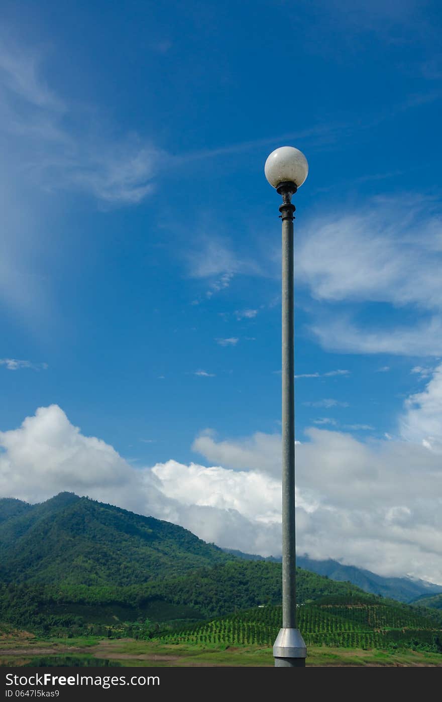 Blue sky and mountain background with luminaire pole on a good weather. Blue sky and mountain background with luminaire pole on a good weather