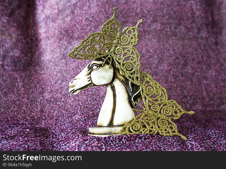 Statuette of horse with gold butterflies on the purple background. Statuette of horse with gold butterflies on the purple background