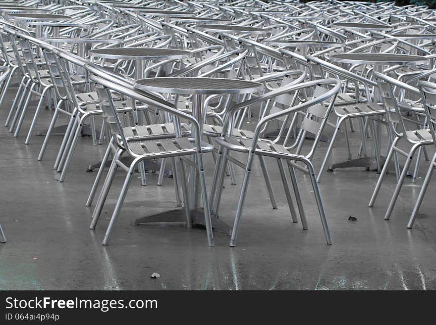 Row of empty silver tables and silver chairs outside a restaurant. Row of empty silver tables and silver chairs outside a restaurant