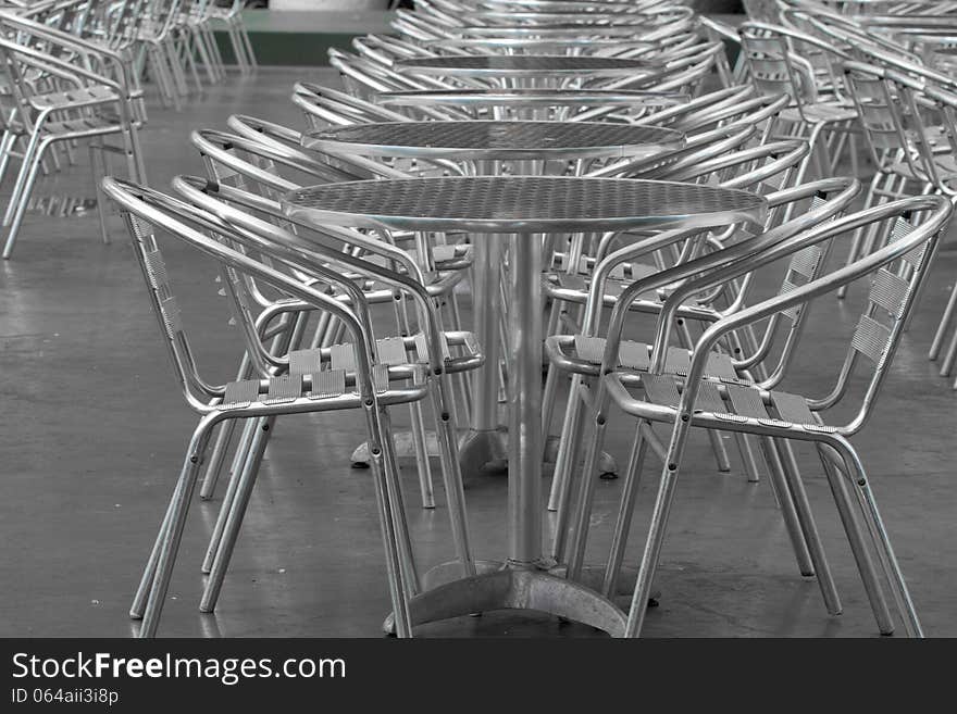 Row of empty silver tables and silver chairs outside a restaurant. Row of empty silver tables and silver chairs outside a restaurant