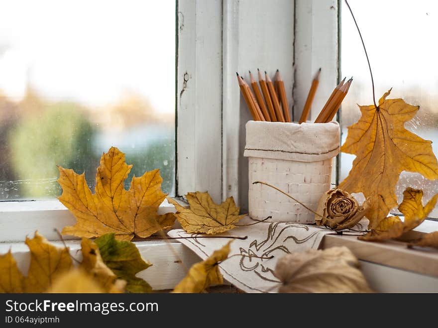 Dry white rose on the window on the background of yellow leaf