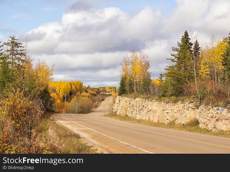 Winding highway between a rock ridge and trees