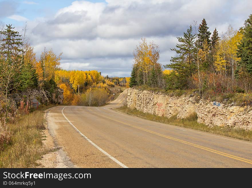 Winding highway between a rock ridge and trees