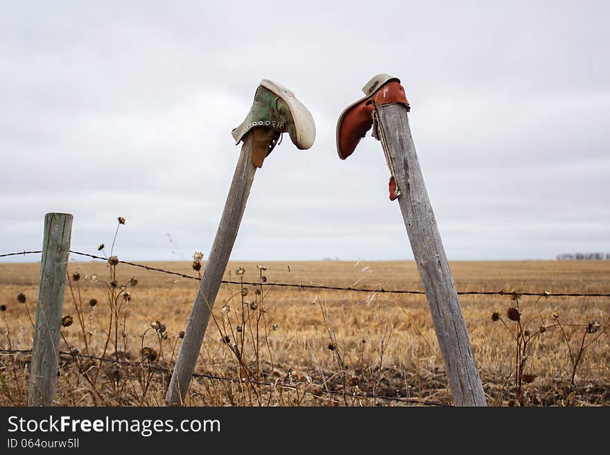 Two boots hanging on fence posts