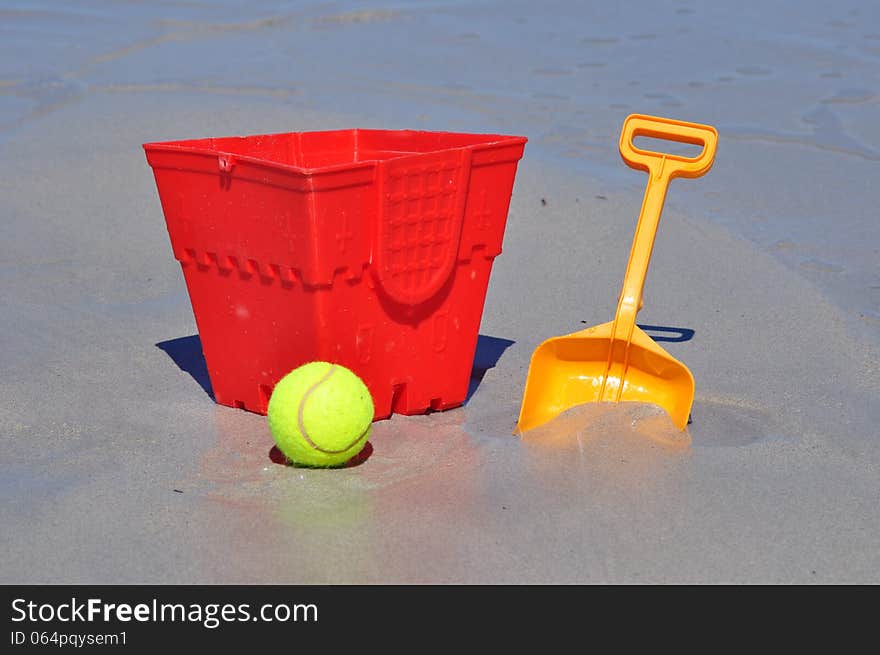 Red bucket spade and ball on the beach