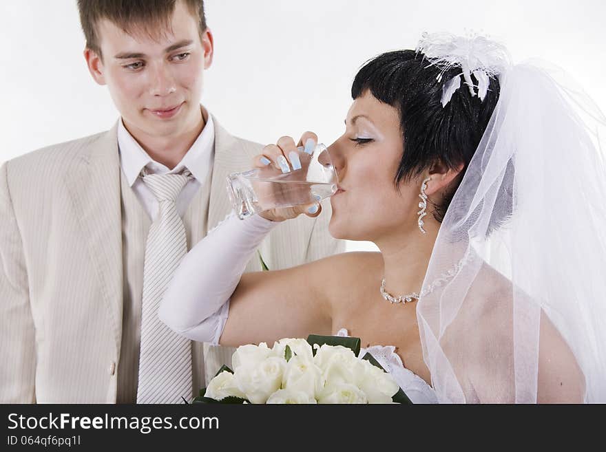 The groom and the bride drink water. White isolated.