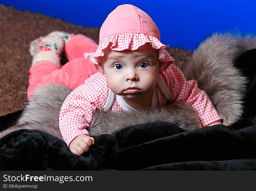 Baby with blue eyes lying on fur and looking at the camera