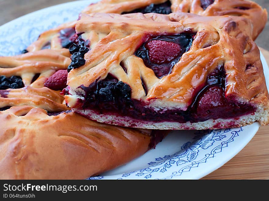 Pie with raspberry and blueberry on a plate closeup