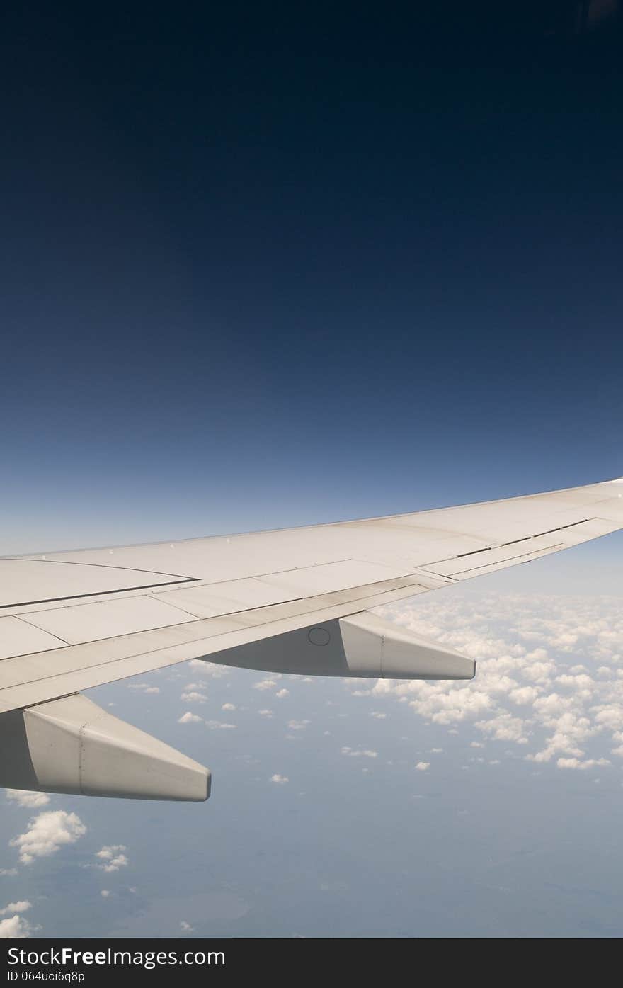 Commercial airplane flying with deep blue sky above and clouds below