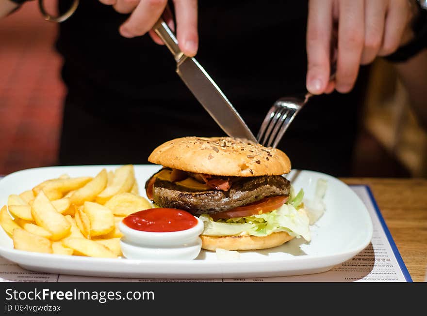 Man eating burger at restaurant (detail)