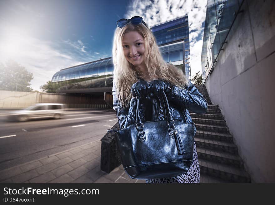 Beautiful girl in leather gloves and a leather jacket on a background of the city