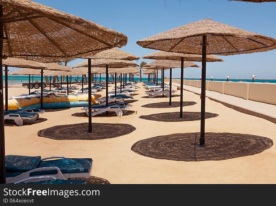 Deserted beach, sunshades, chaise lounges