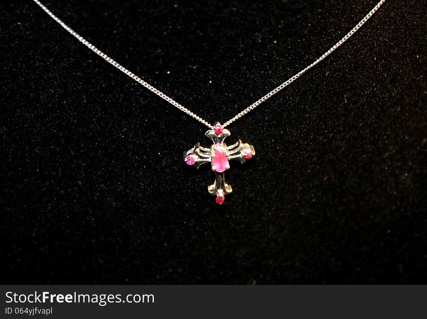 Ruby cross necklace on a black background