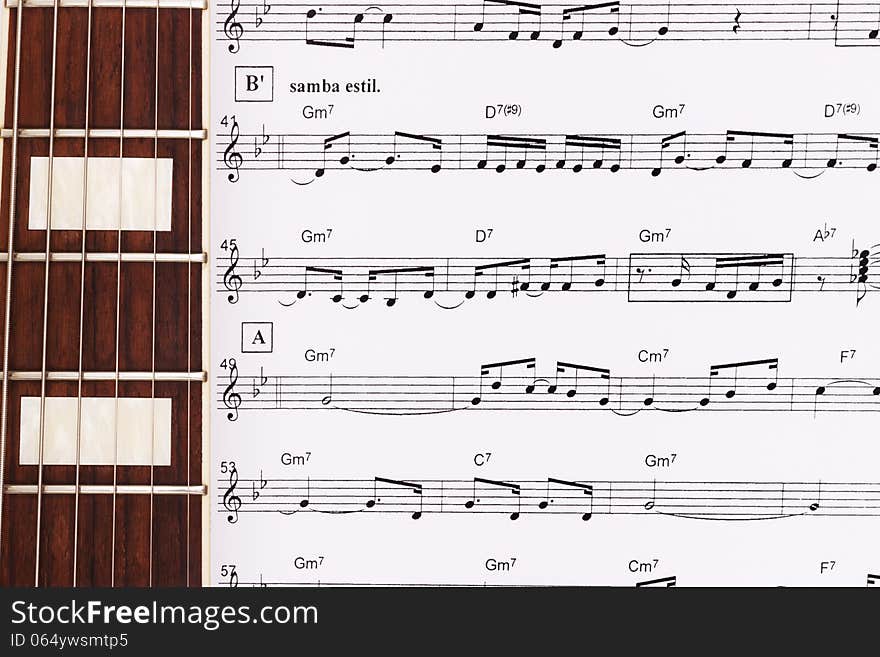 Guitar Neck Laying Across Sheet Music