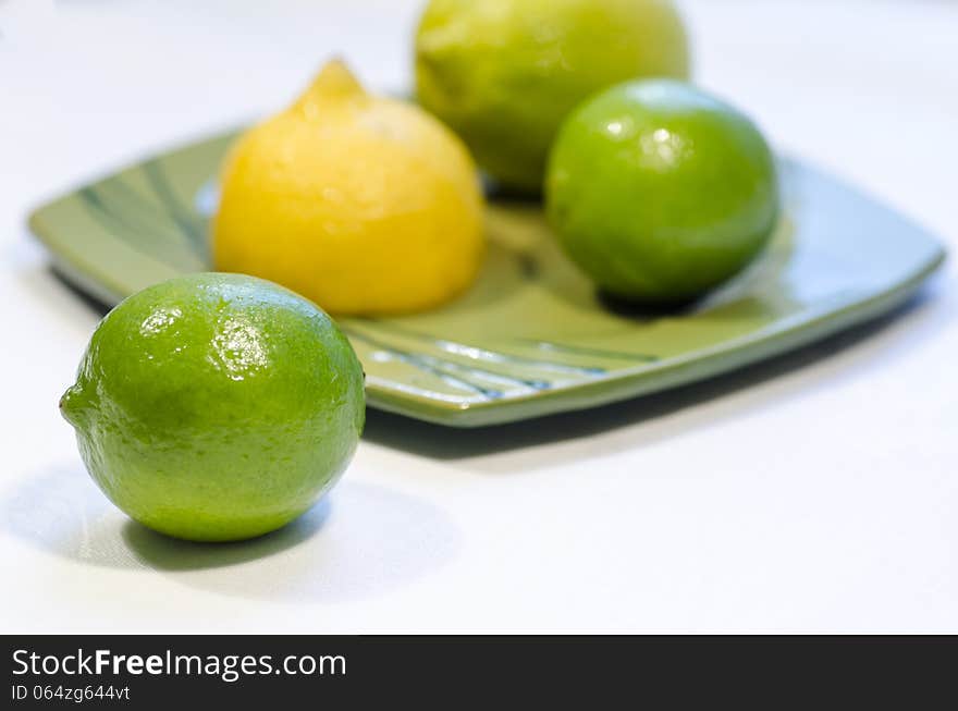 Lemons and limes on a green plate, blurred background. From the series Healthy Eating