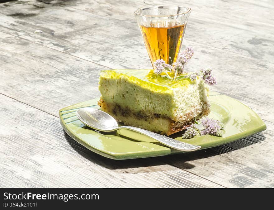 Slice of lime cheesecake decorated with mint flowers and glass of cognac. From series Summer desserts