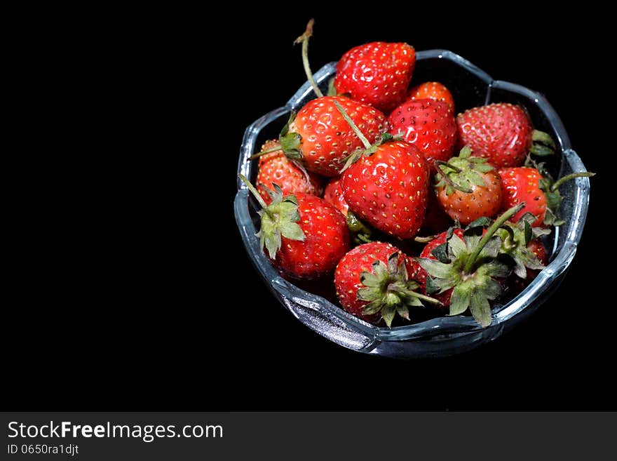 A bowl of strawberry, over black background