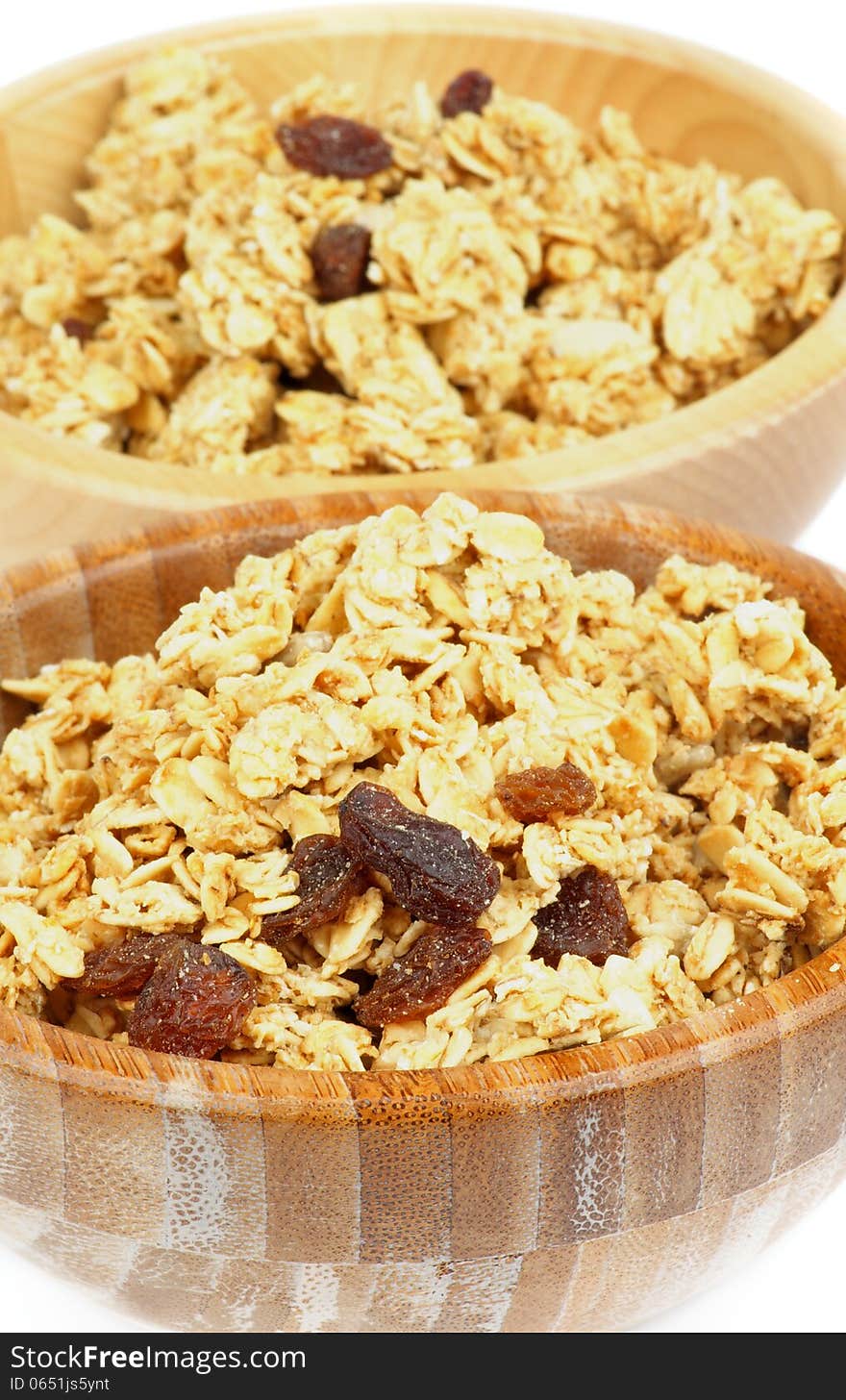 Breakfast Cereal Flakes with Slices of Nuts and Raisins closeup in Two Wooden Bowls. Breakfast Cereal Flakes with Slices of Nuts and Raisins closeup in Two Wooden Bowls