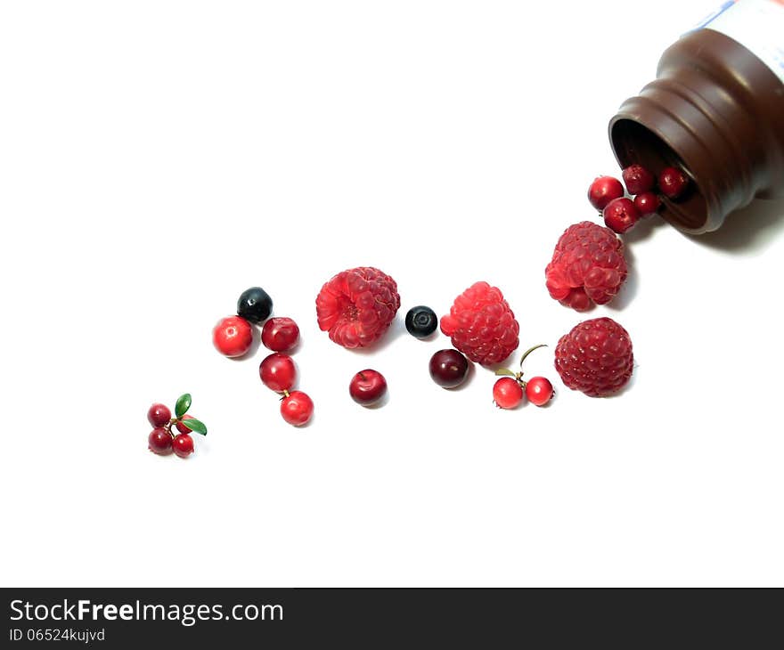 Berries spilling out of pills bottle isolated on white