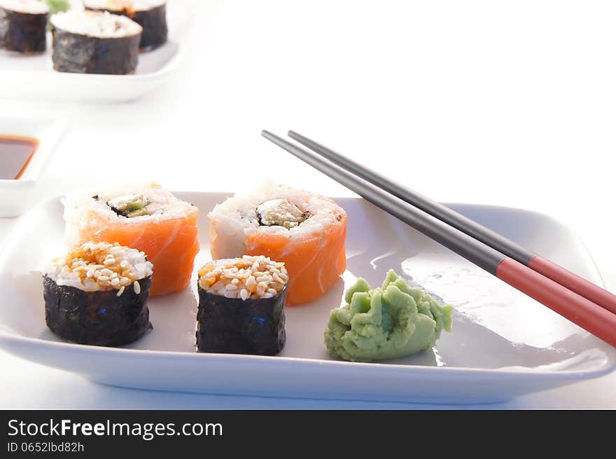 Sushi, rolls, wasabi and chopsticks on a white plate. Sushi, rolls, wasabi and chopsticks on a white plate