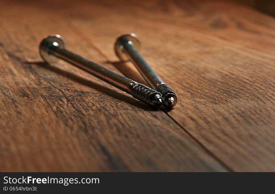 Two long screws on the wooden floor. Two long screws on the wooden floor